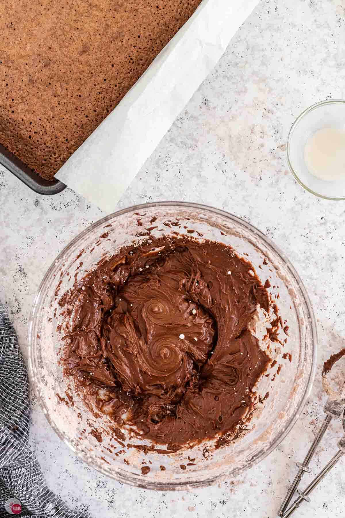 frosting being mixed in a clear bowl