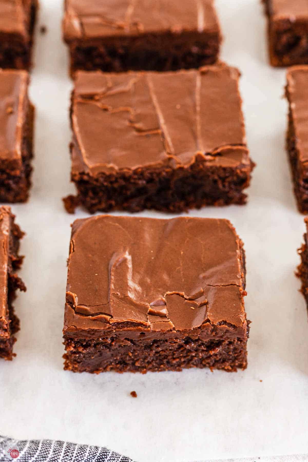 squares of Lunch Lady Brownies on a piece of parchment paper