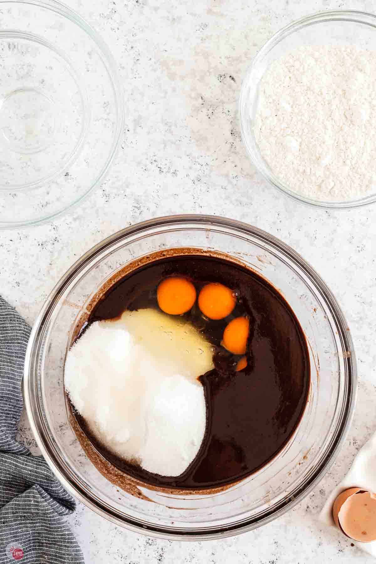 clear bowl with cocoa, sugar, and eggs