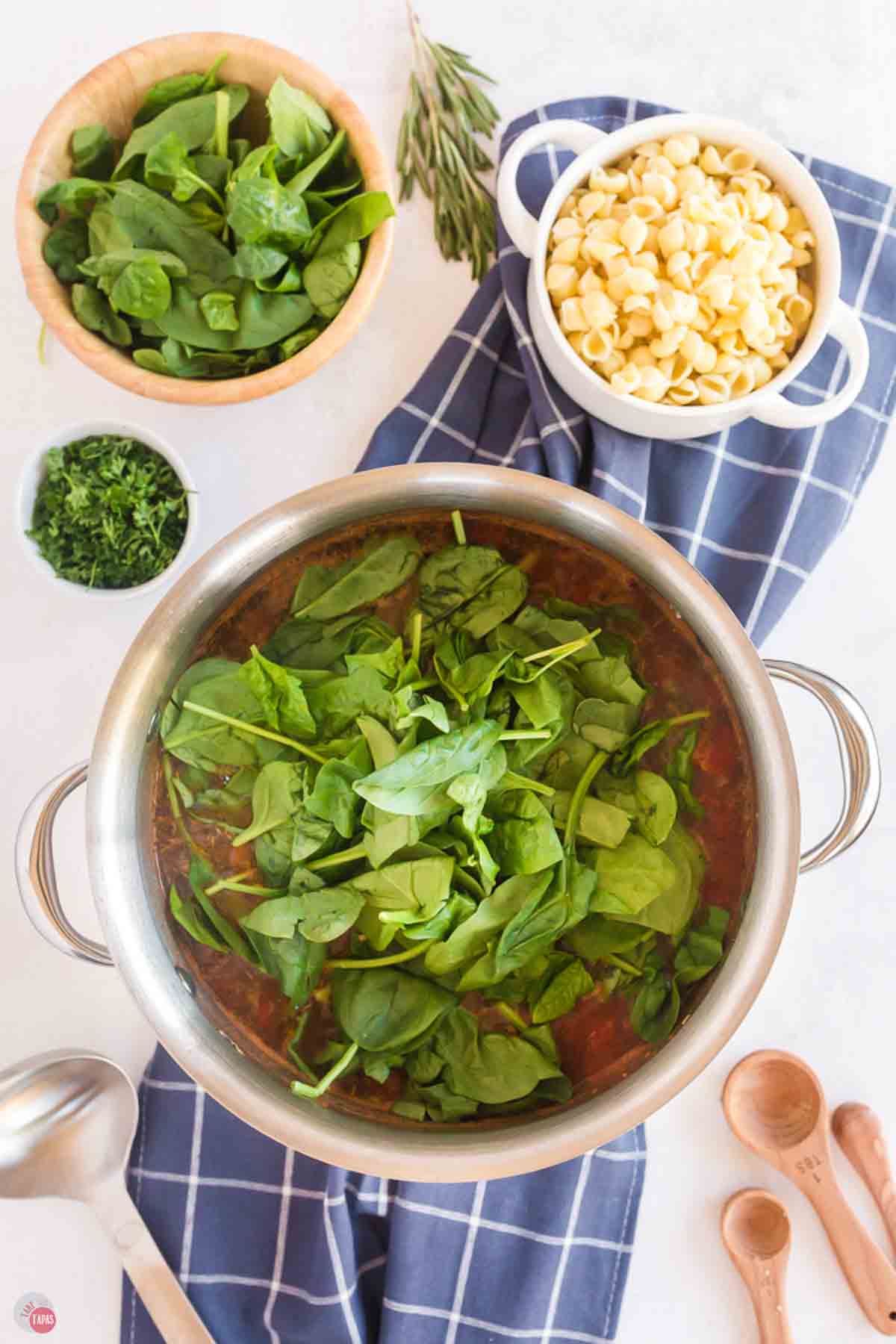 silver pot with broth and a pile of fresh spinach on top