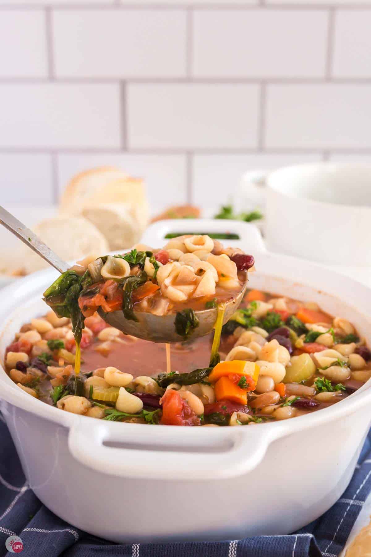 ladle scooping some soup out of a large white pot
