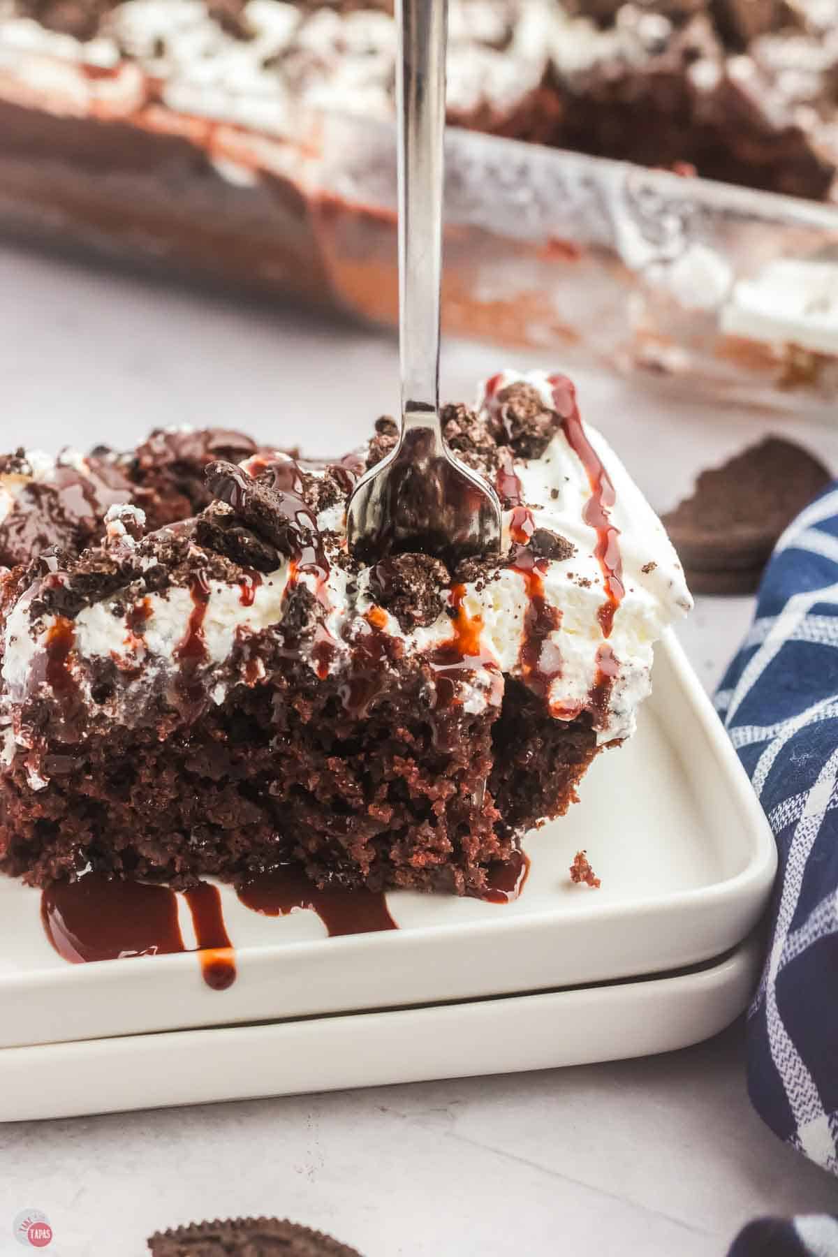 slice of chocolate cake one a white plate with a fork sticking out of the top