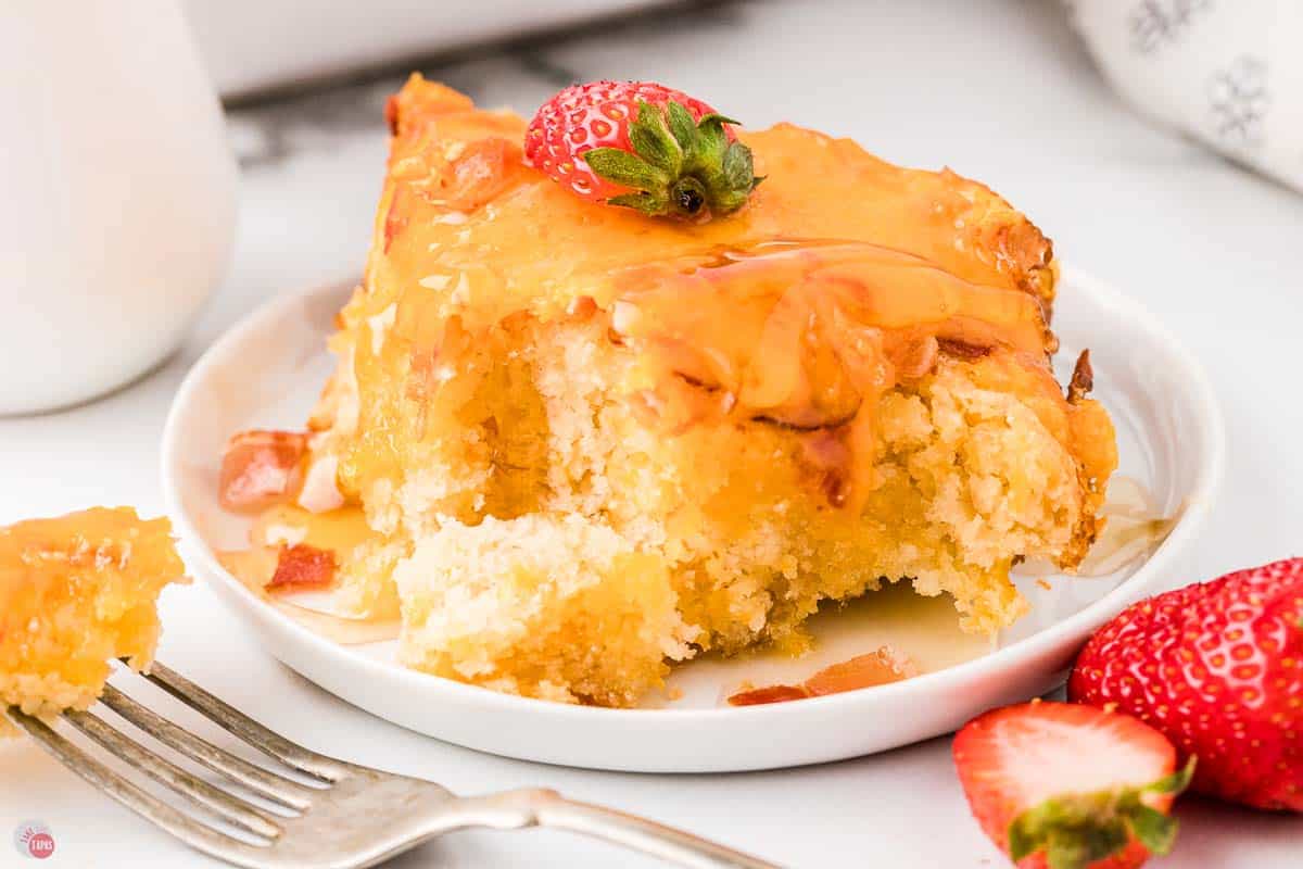 slices of pancake casserole on a white plate and topped with syrup and sliced strawberries