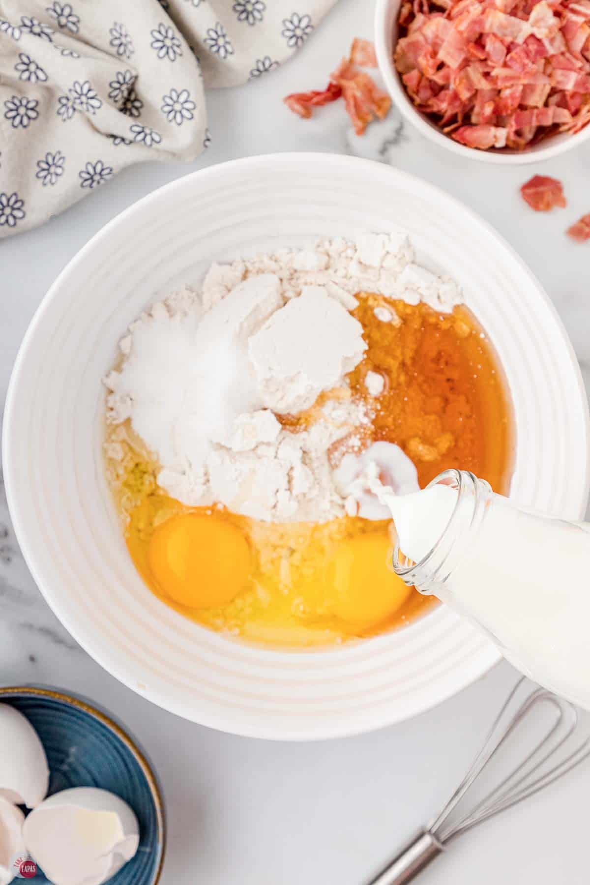 white mixing bowl with eggs, milk, syrup, and pancake mix