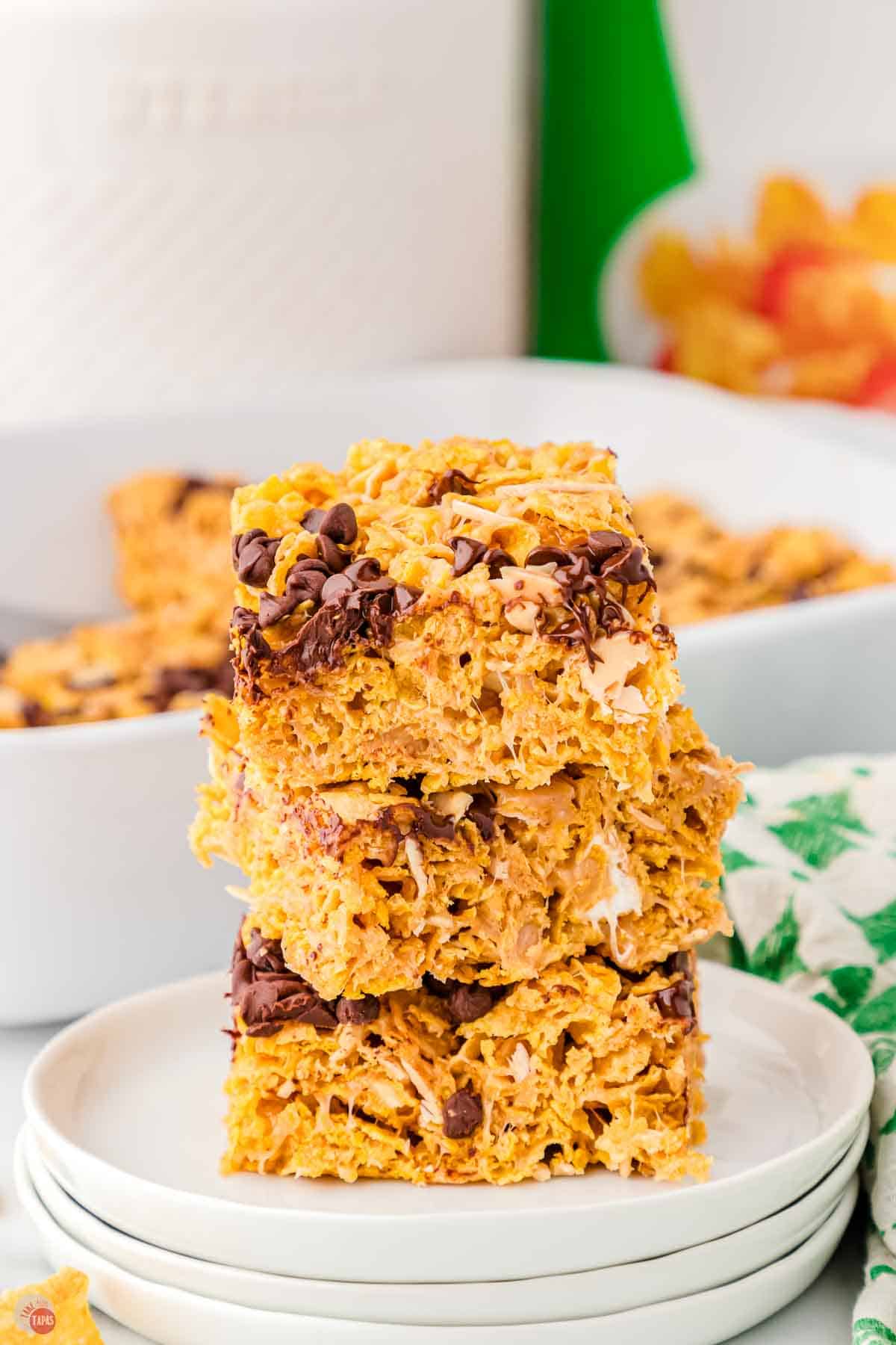 stack of peanut butter bars with cornflakes on a white plate and a green and white napkin