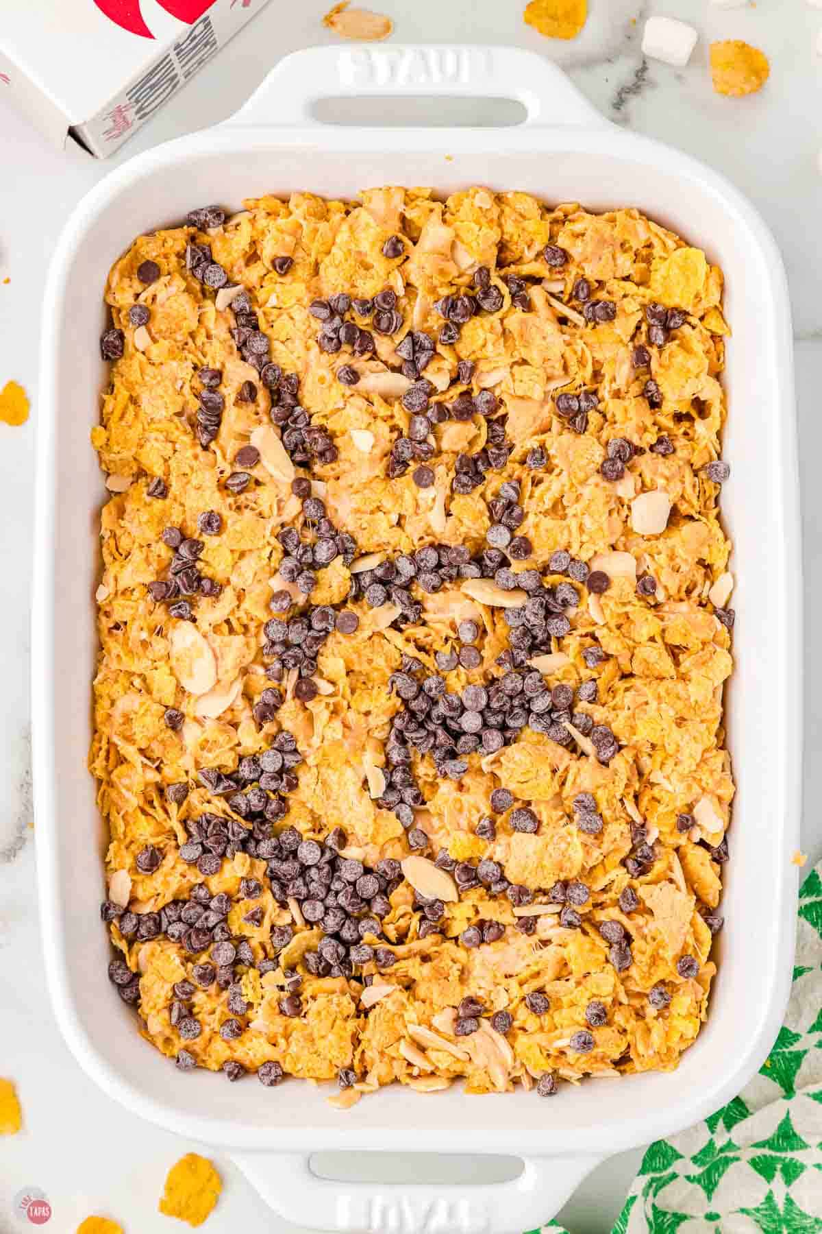rectangle white casserole dish filled with peanut butter cornflake mixture topped with mini chocolate chips