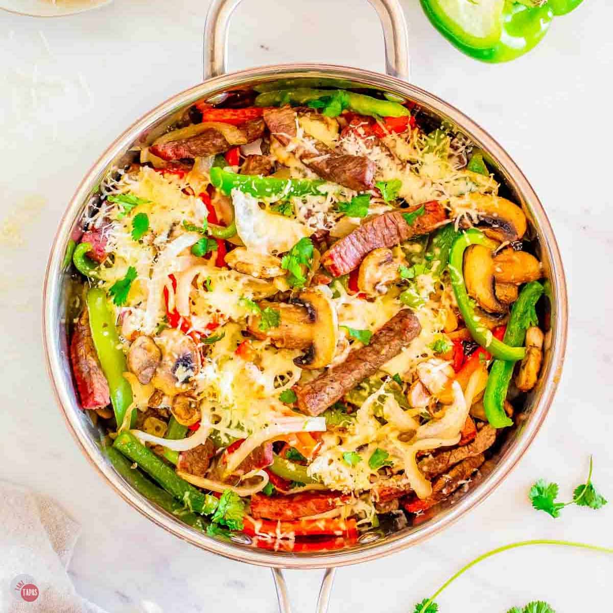 skillet full of philly cheesesteak ingredients