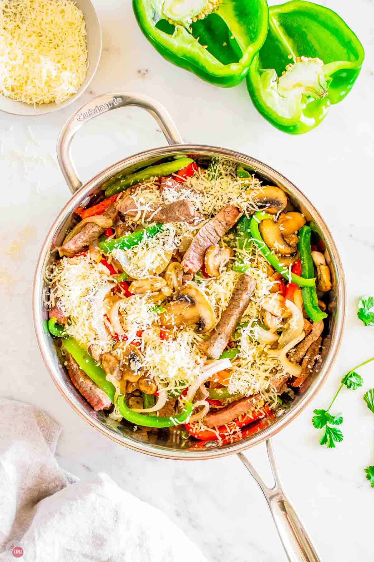 philly cheesesteak fillings cooking in a silver skillet
