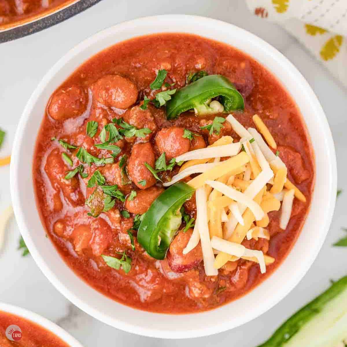bowl of rotel chili topped with shredded cheese and jalapeno slices