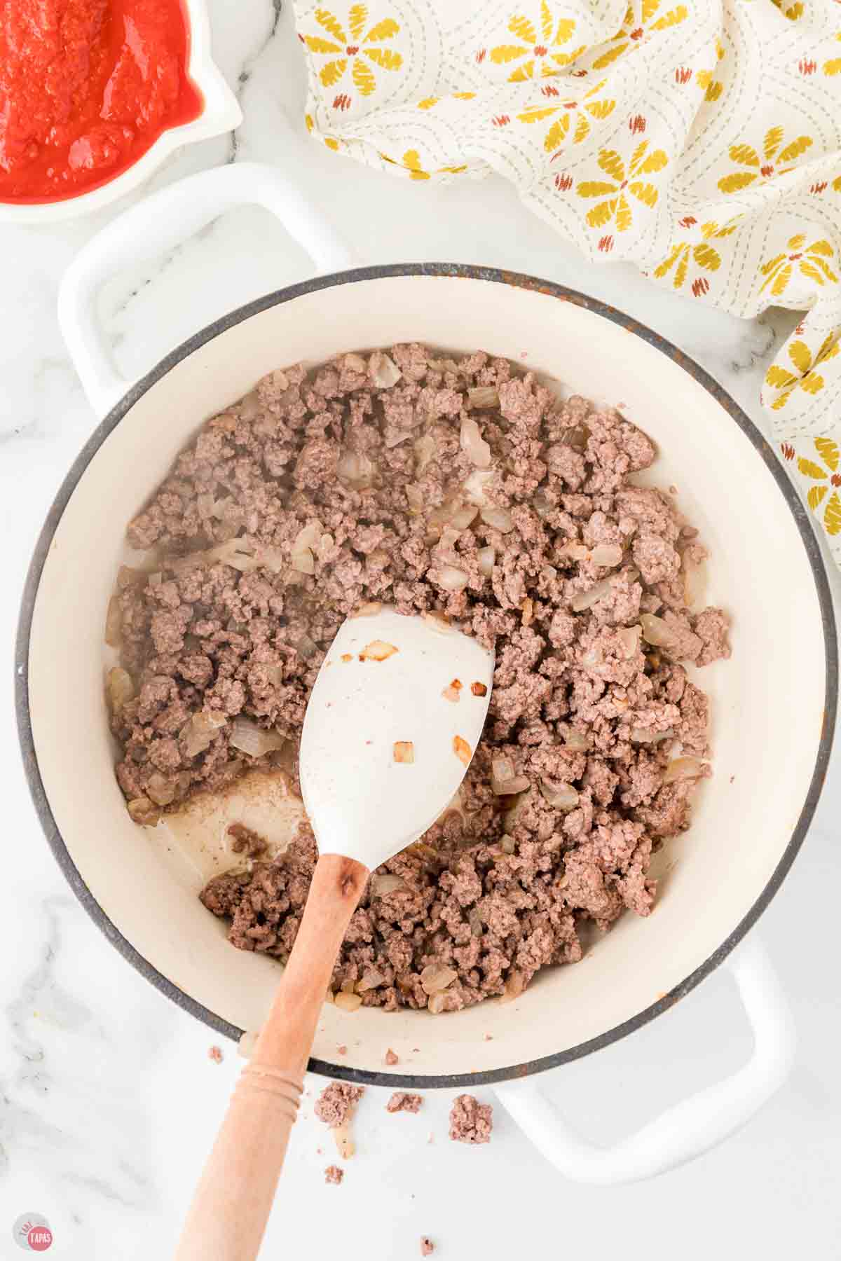 ground beef cooking in a white soup pot