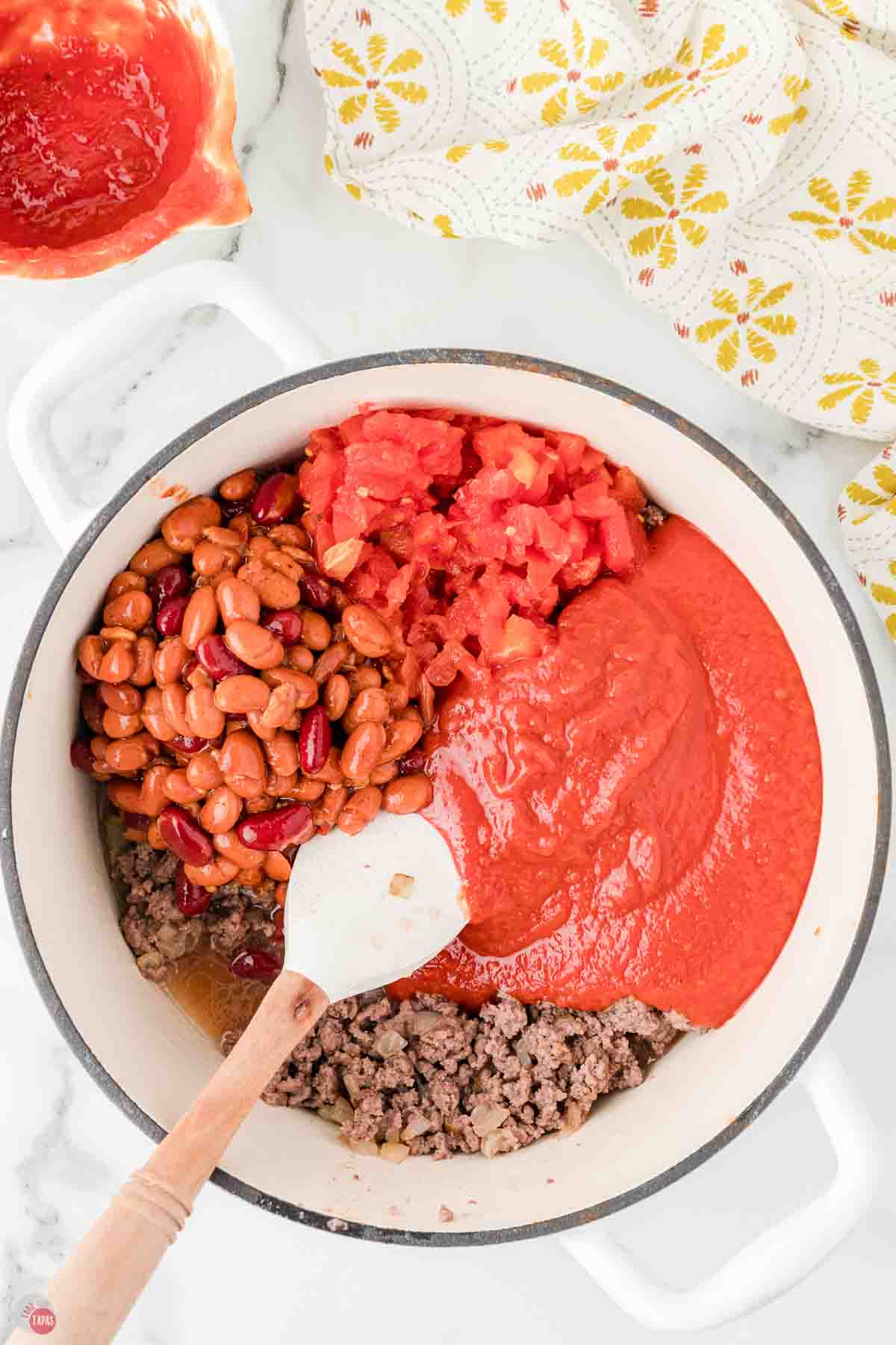 white soup pot with cooked ground beef, tomatoes, sauce, and beans