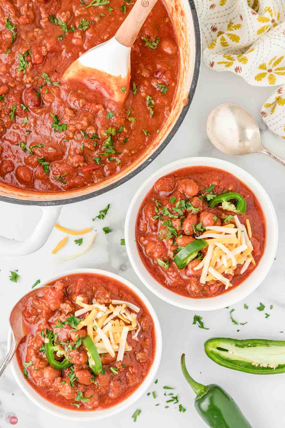 two bowls of chili with a pot of soup next to it