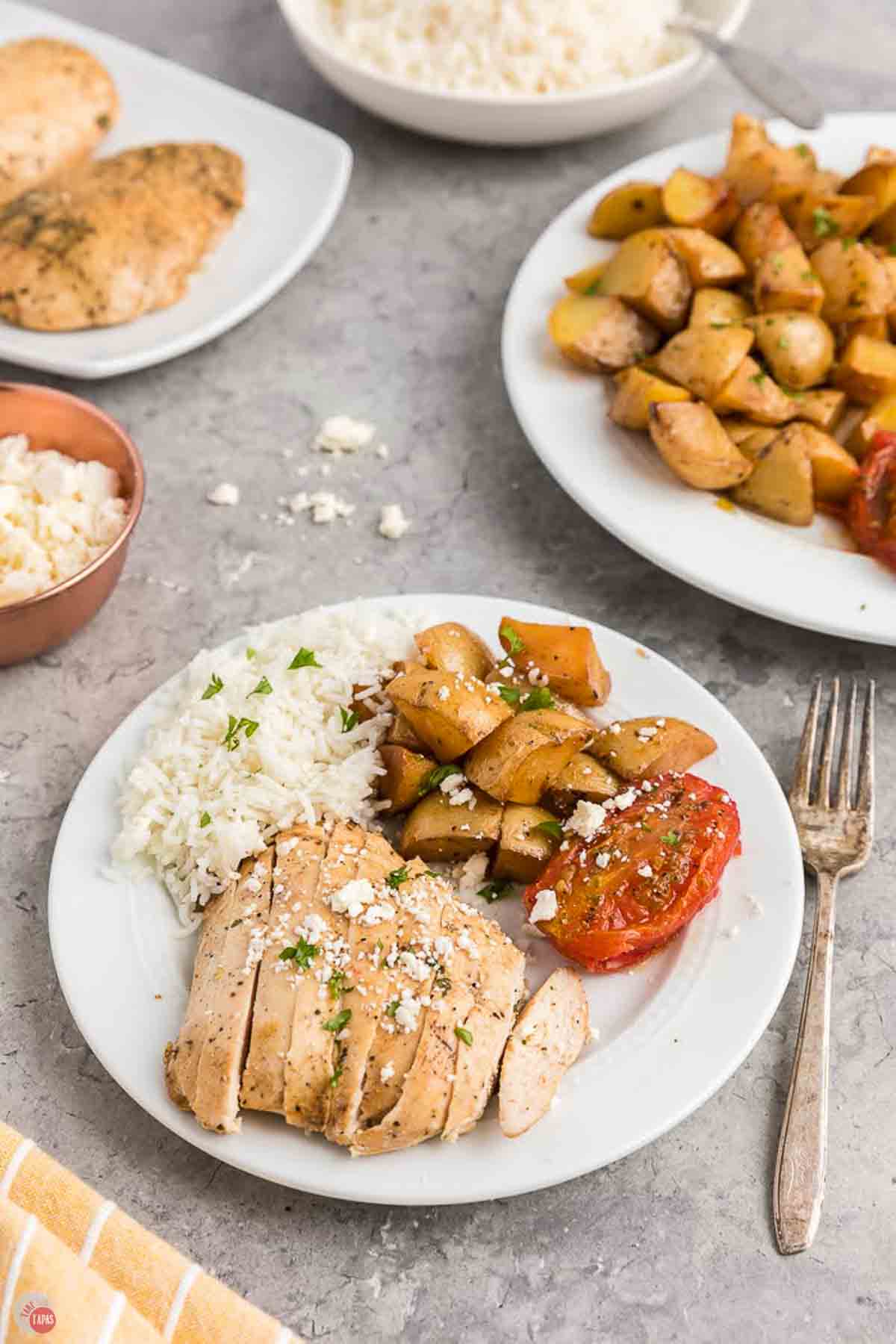 plate of chicken, tomatoes, and potatoes, topped with feta cheese