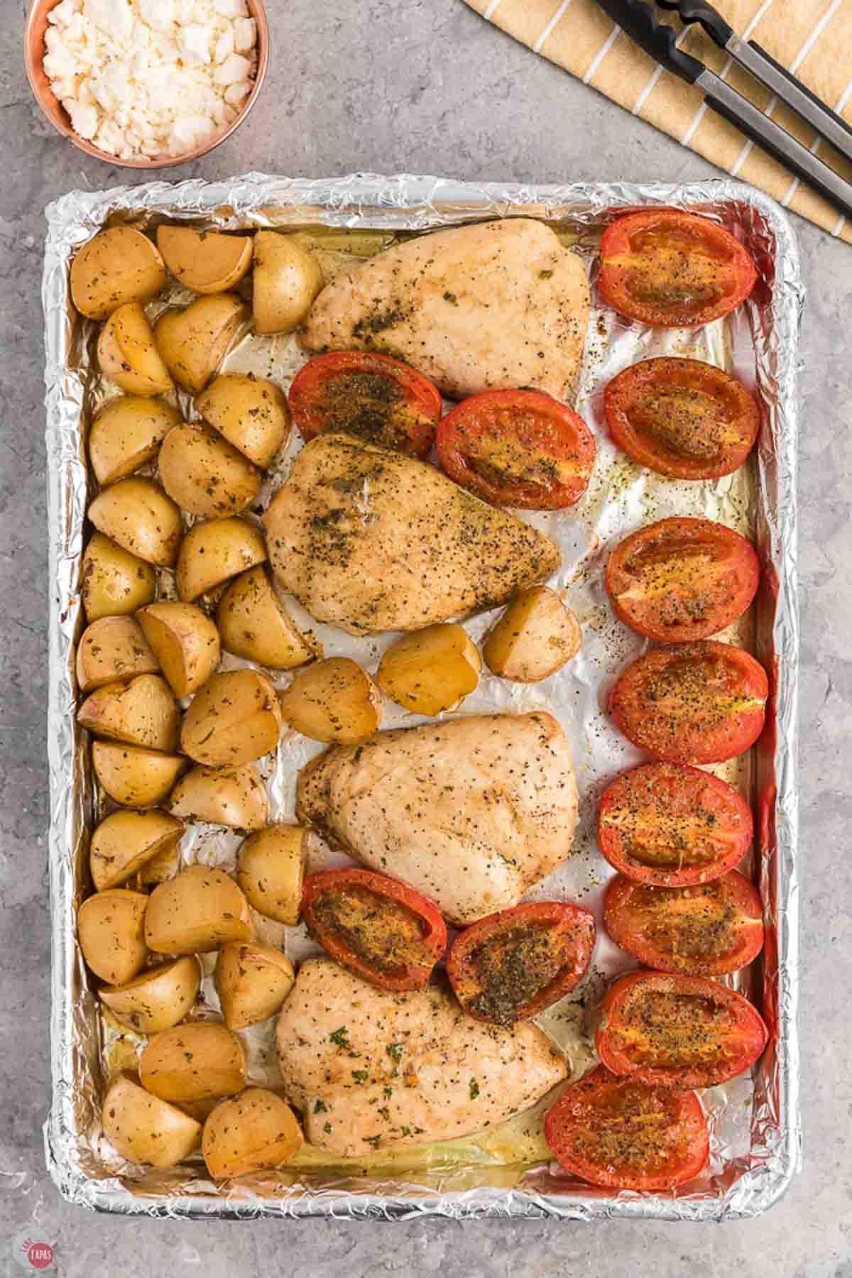chicken, Roma tomatoes, and baby potatoes roasted on a baking sheet