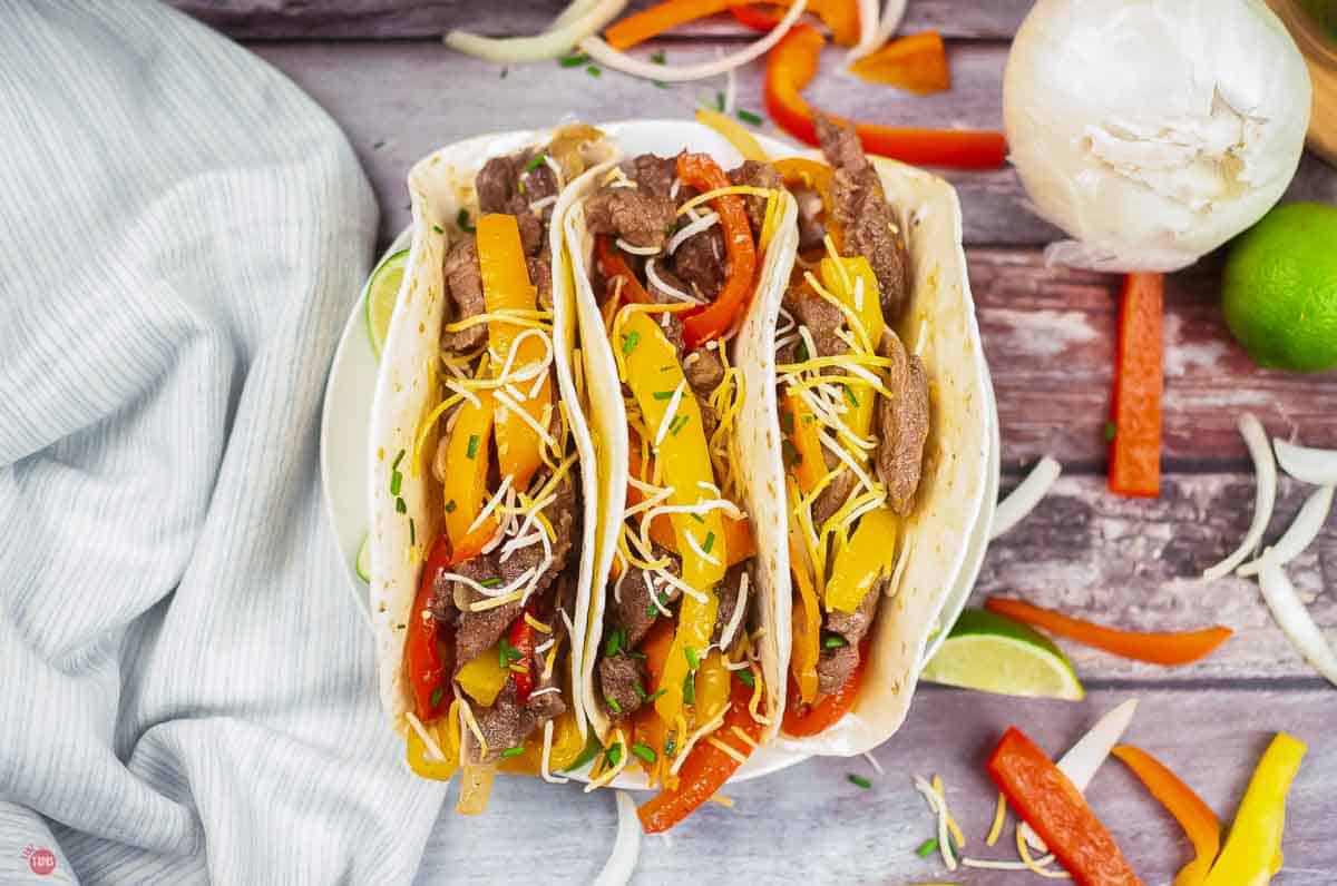 plate with three tortillas filled with steak fajitas
