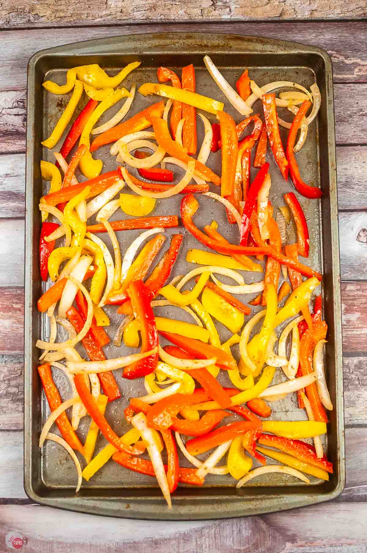 baked sheet topped with sliced bell peppers and onions