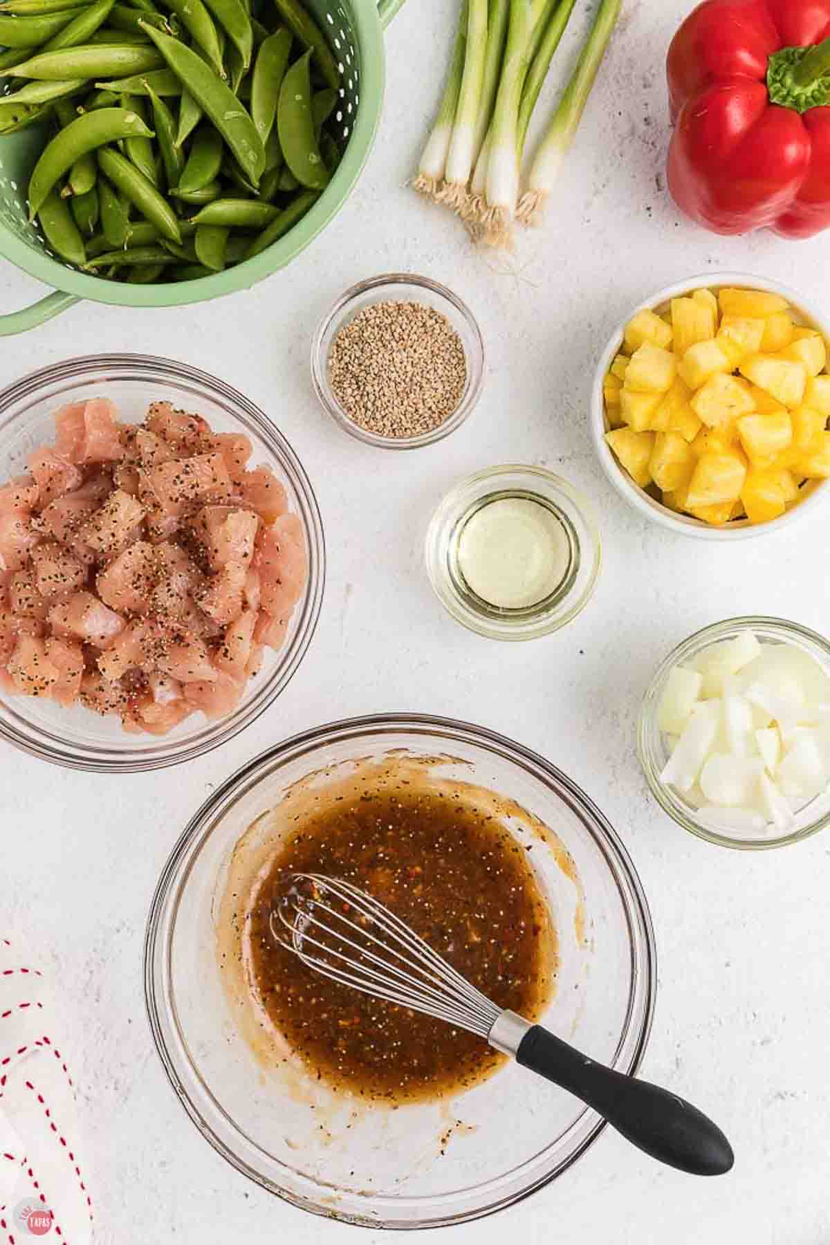 small bowls of individual ingredients and a bowl of marinade being whisked