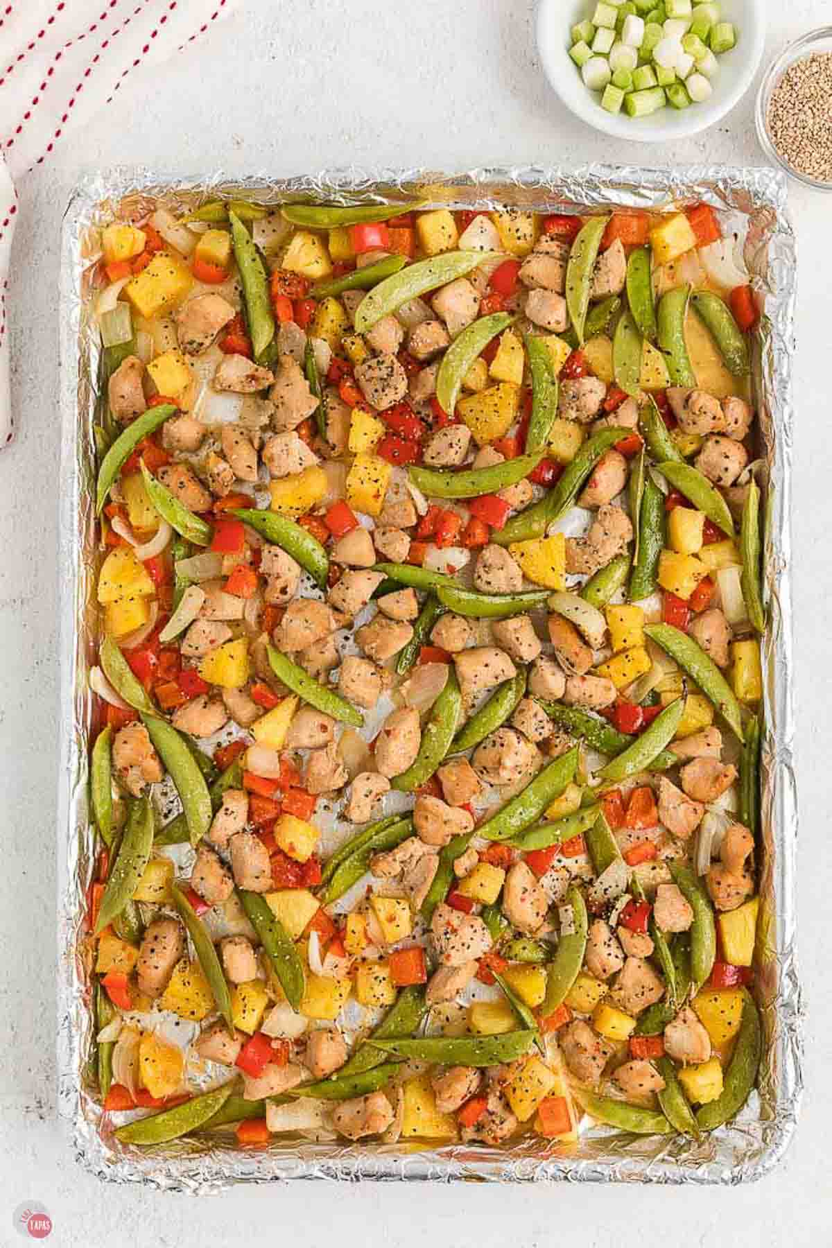 sweet and sour chicken with vegetables on a baking sheet