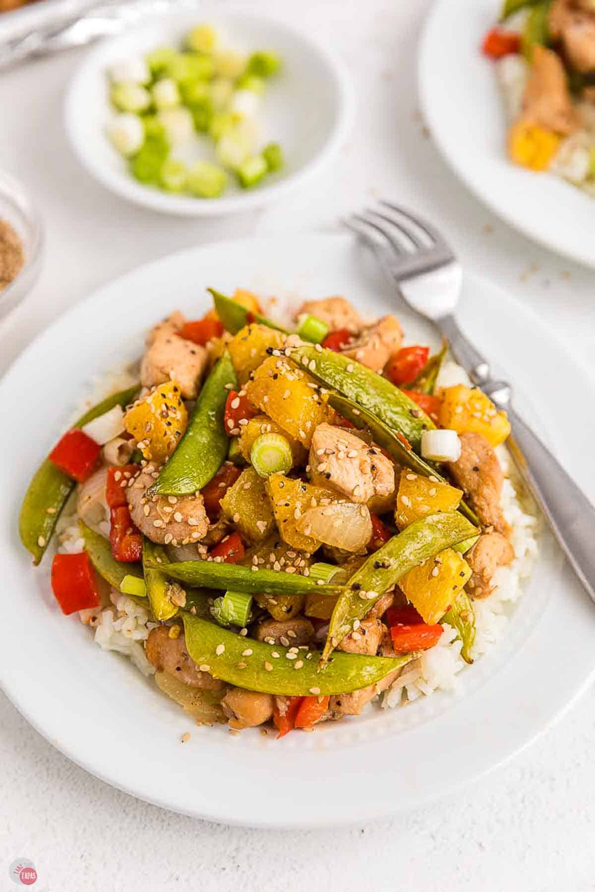 close up of a plate of chicken and vegetables over rice