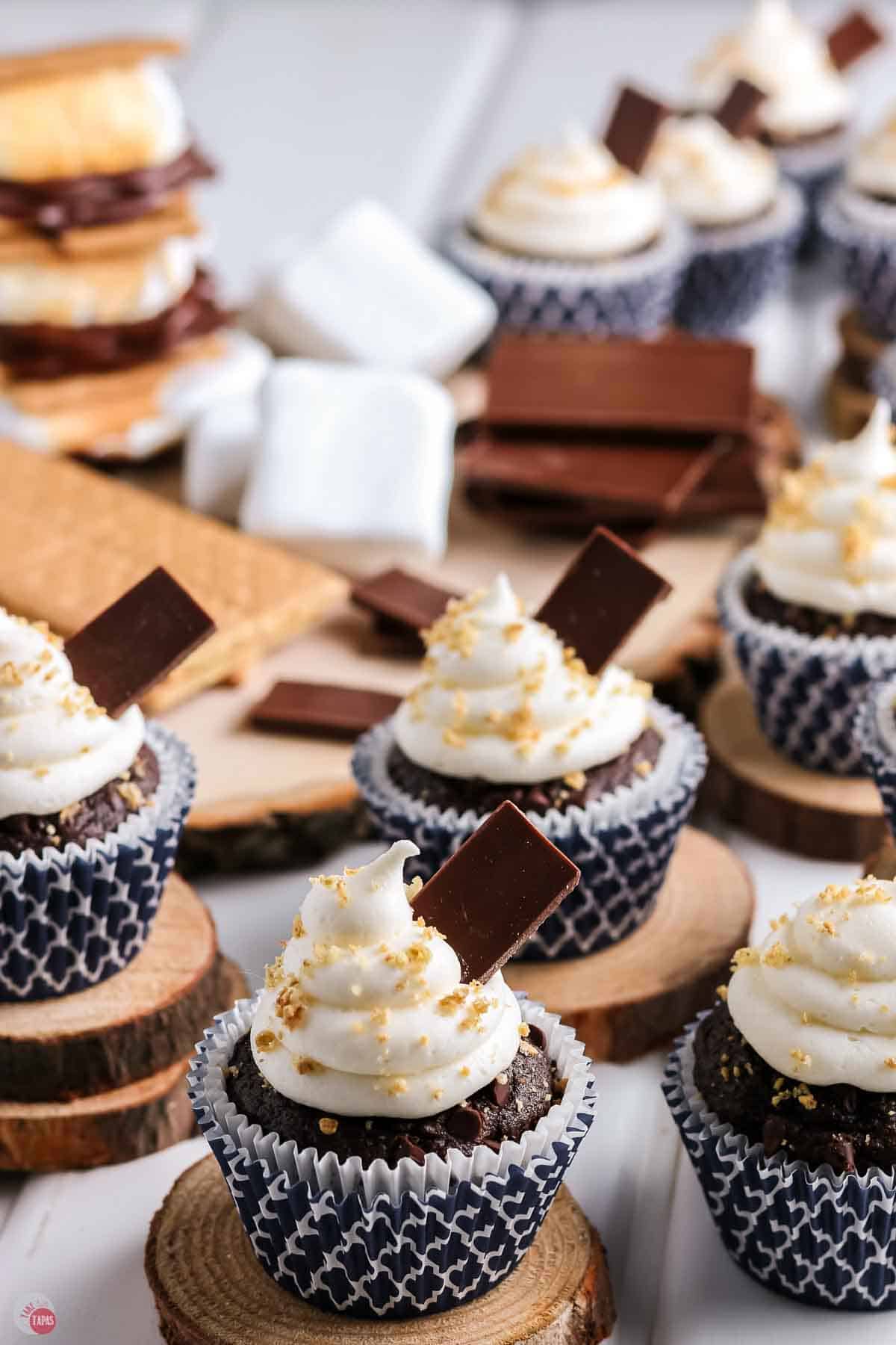 s'mores cupcakes topped with marshmallow frosting and graham cracker crumbs