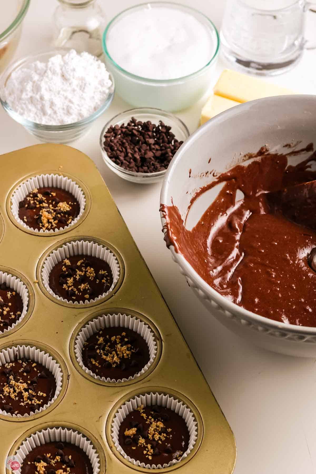 cupcake batter in a muffin pan next to a bowl