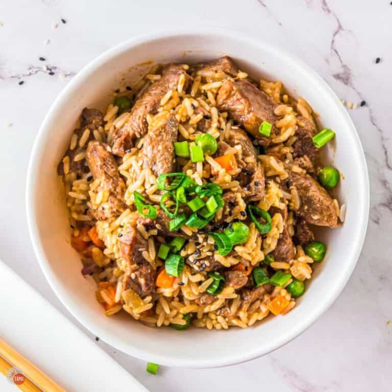 white bowl of steak fried rice with two chopsticks next to it