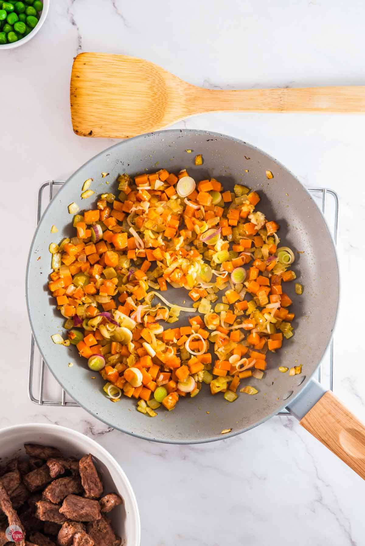 carrots and onions cooking in a skillet