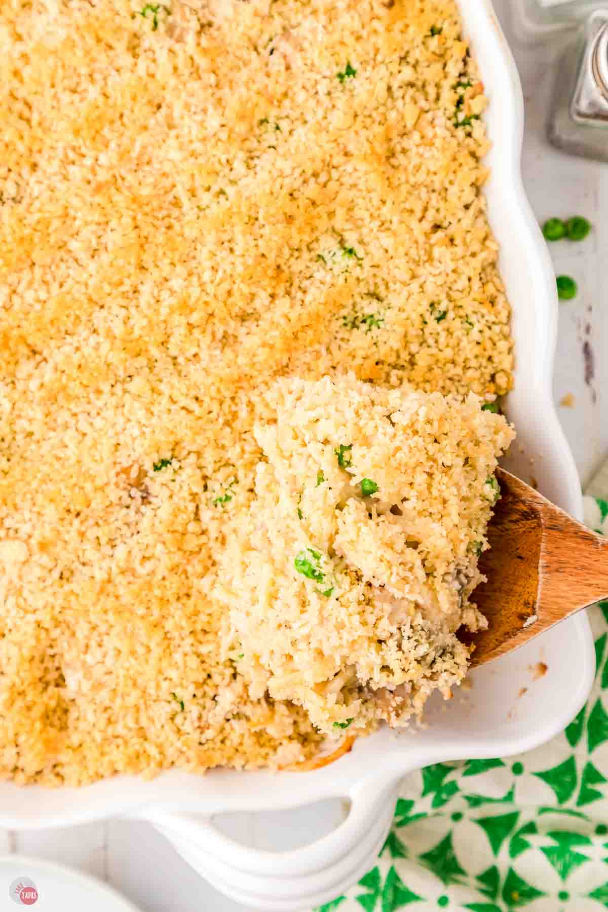 wood spoon scooping casserole out of a dish