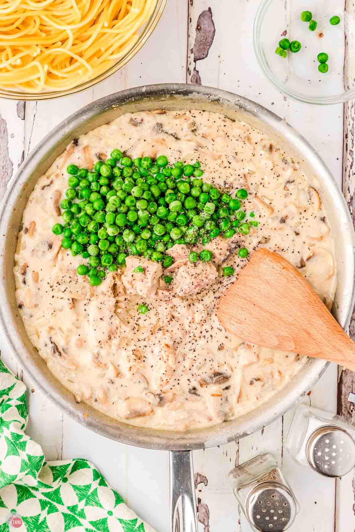 creamy mushroom sauce stirring in a skillet with frozen peas on top