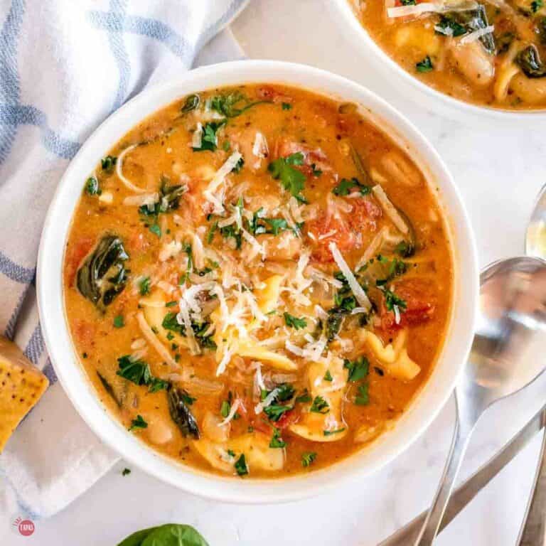 bowl of tortellini soup next to a blue and white napkin