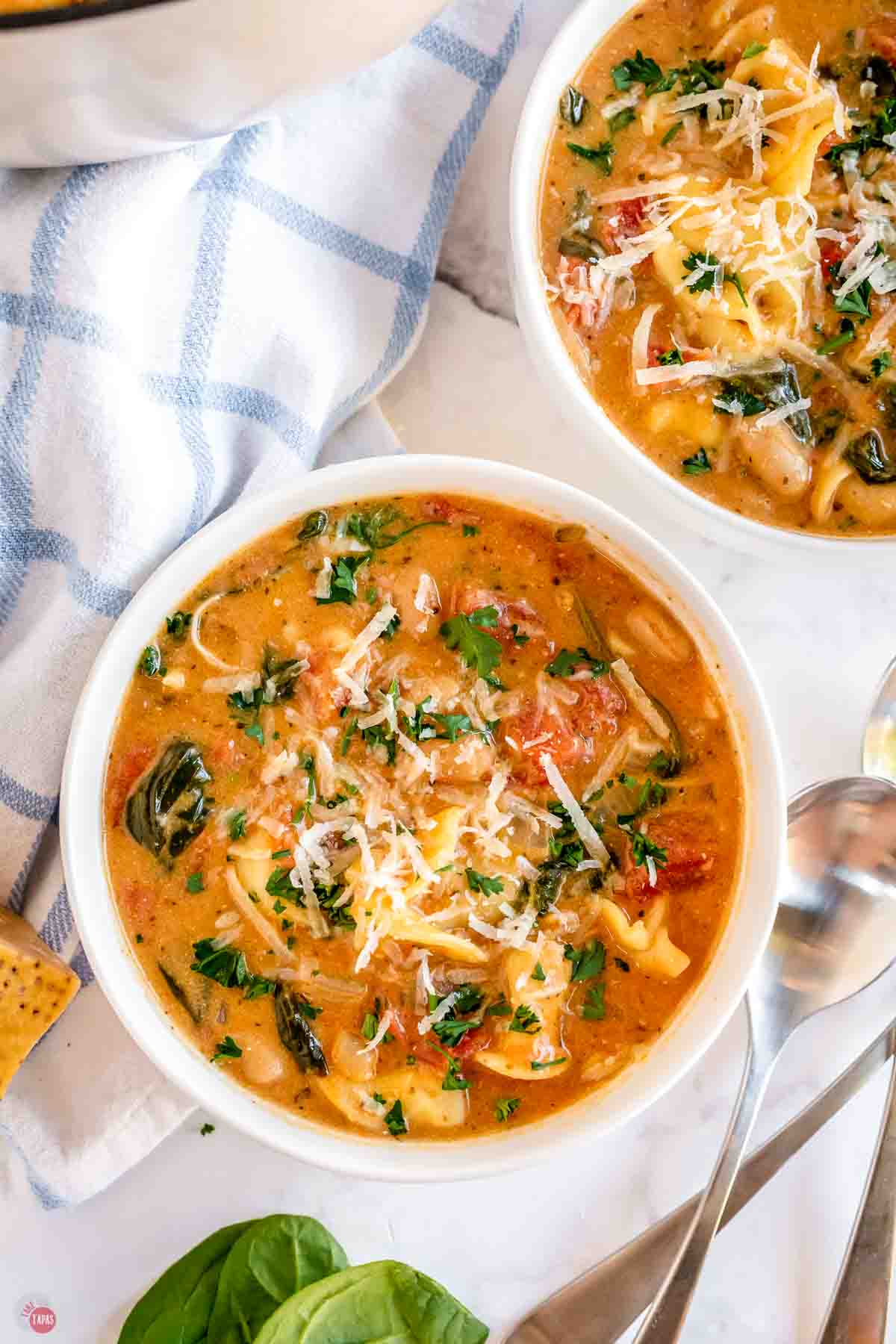 bowl of tortellini soup next to a blue and white napkin
