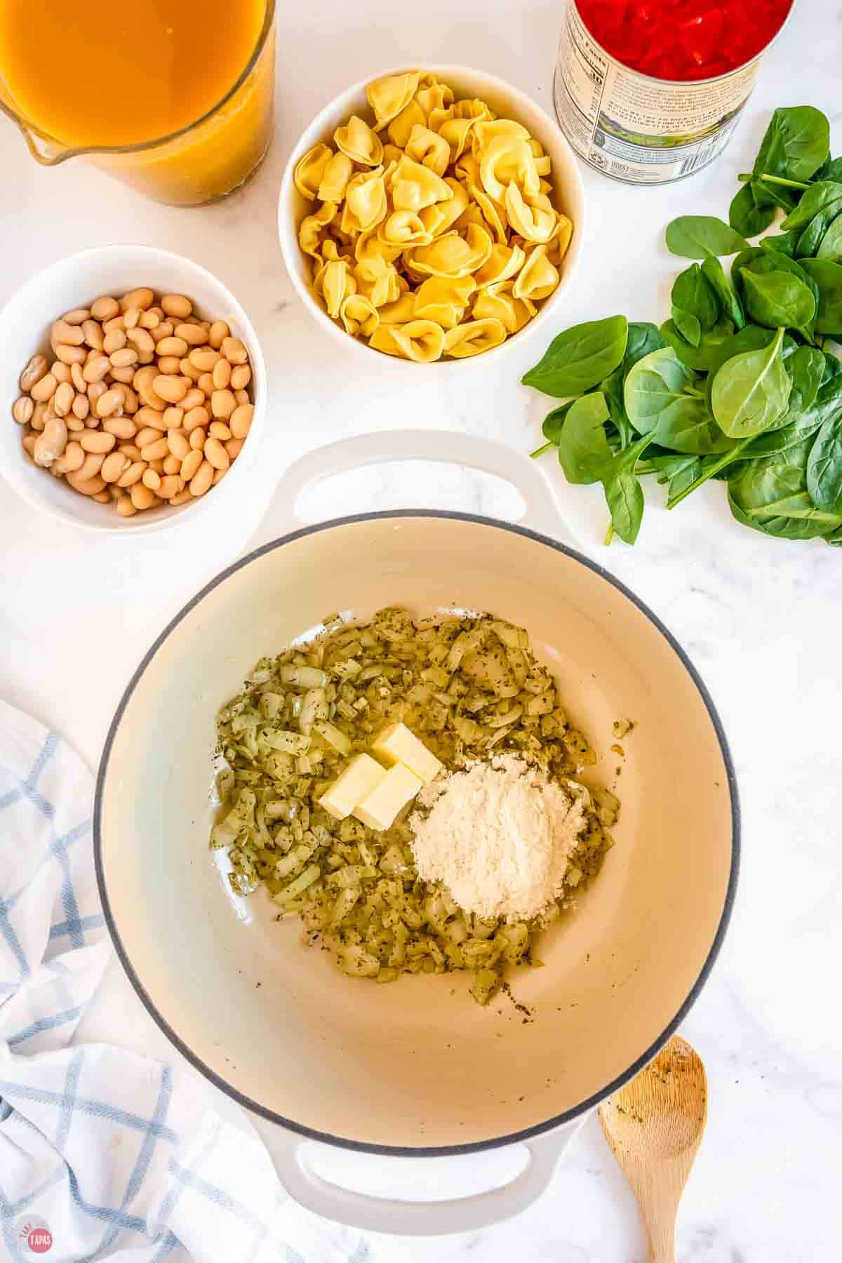 onions and spices cooking in a white soup pot