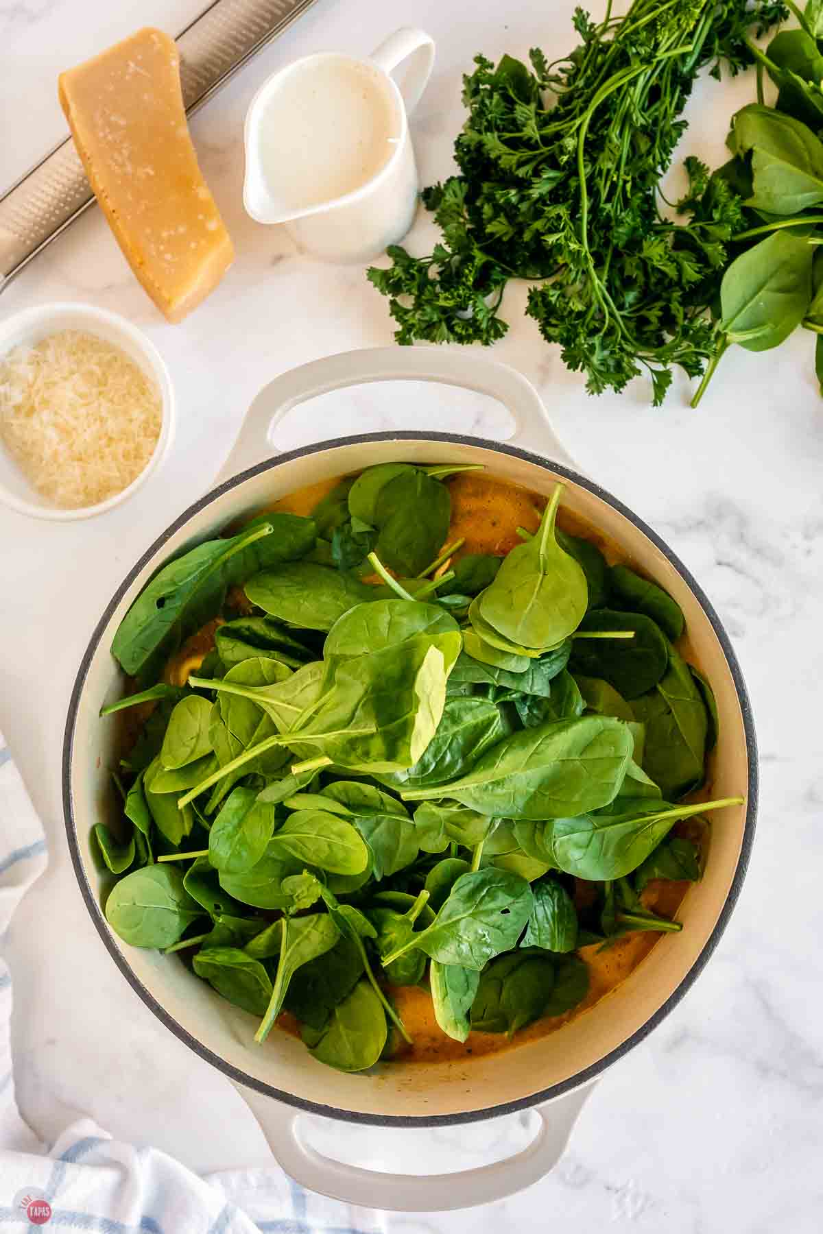 soup pot with broth and fresh spinach piled on top