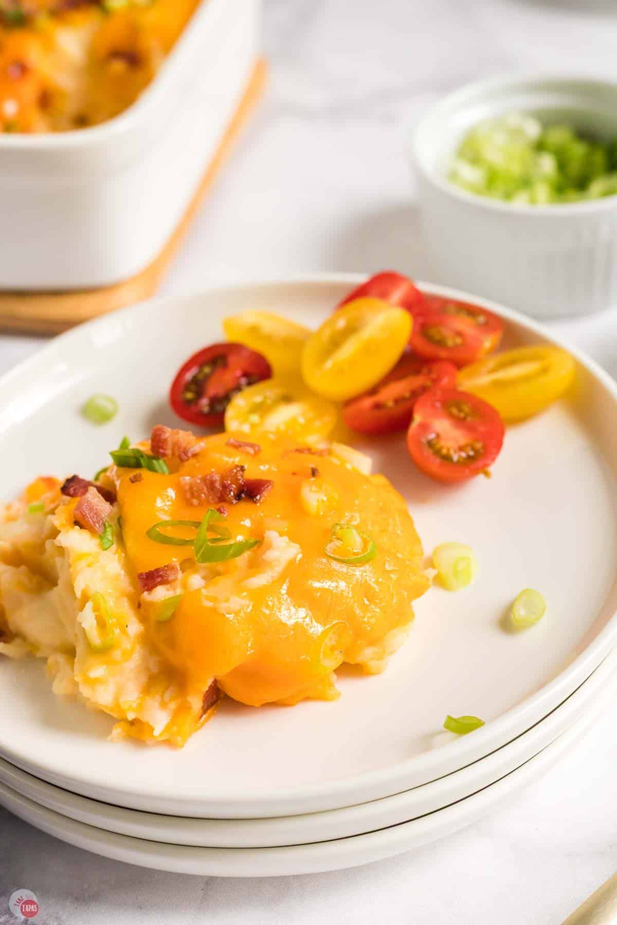 close up of plate with scoop of potato casserole and sliced tomatoes