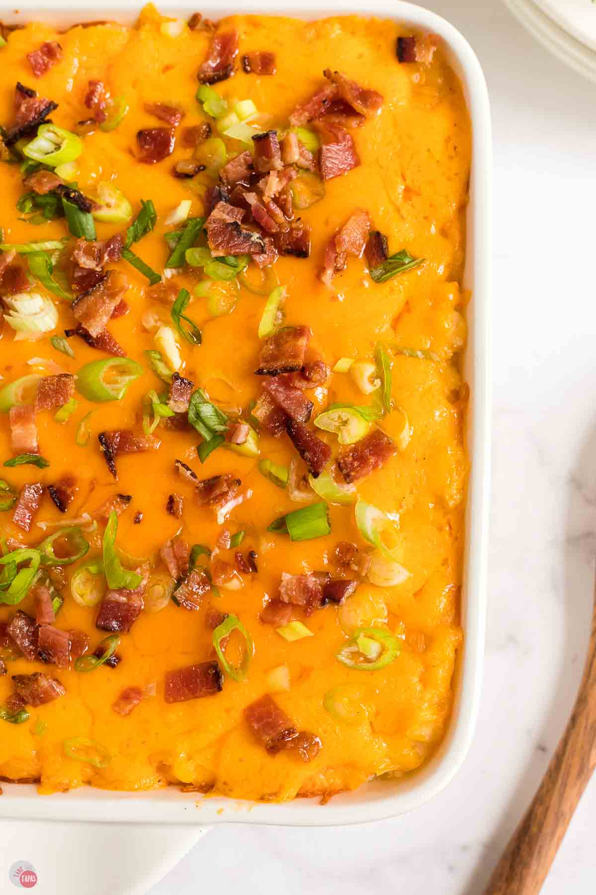 close up of baked potato casserole topped with melted cheese and crumbled bacon