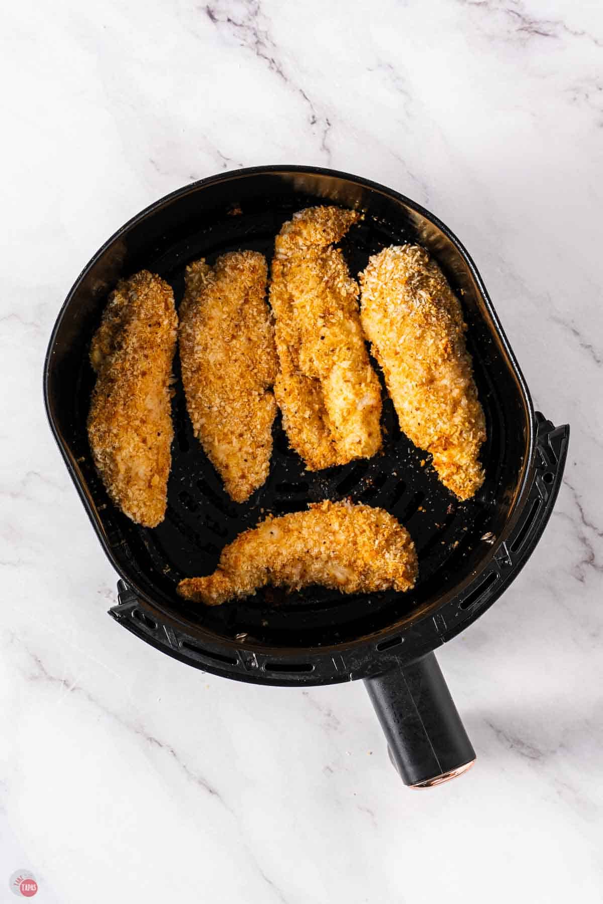 air fryer basket with cooked chicken tenders in it