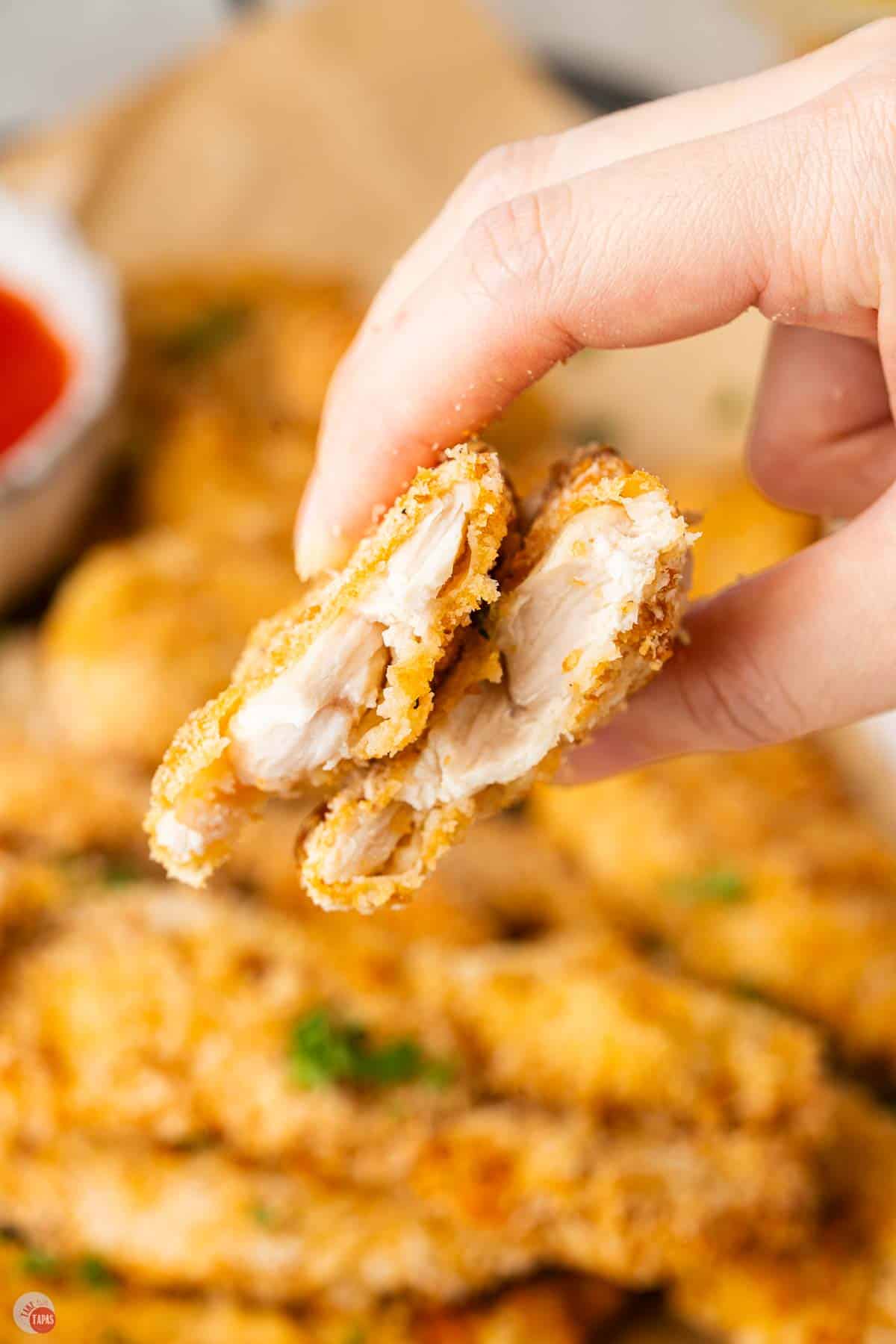 hand holding a chicken tender cut in half