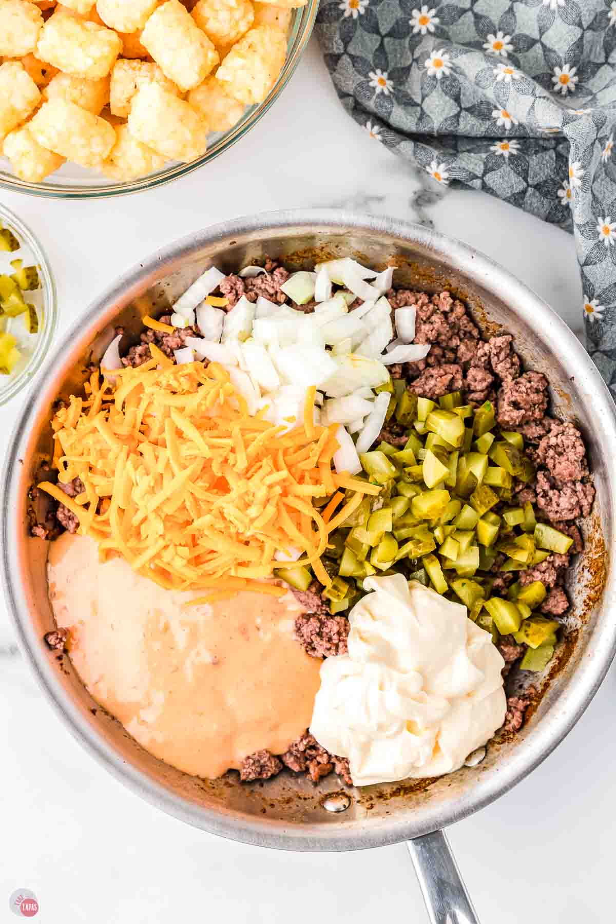 skillet with ground beef, pickles, diced onions, mayo, and cheese
