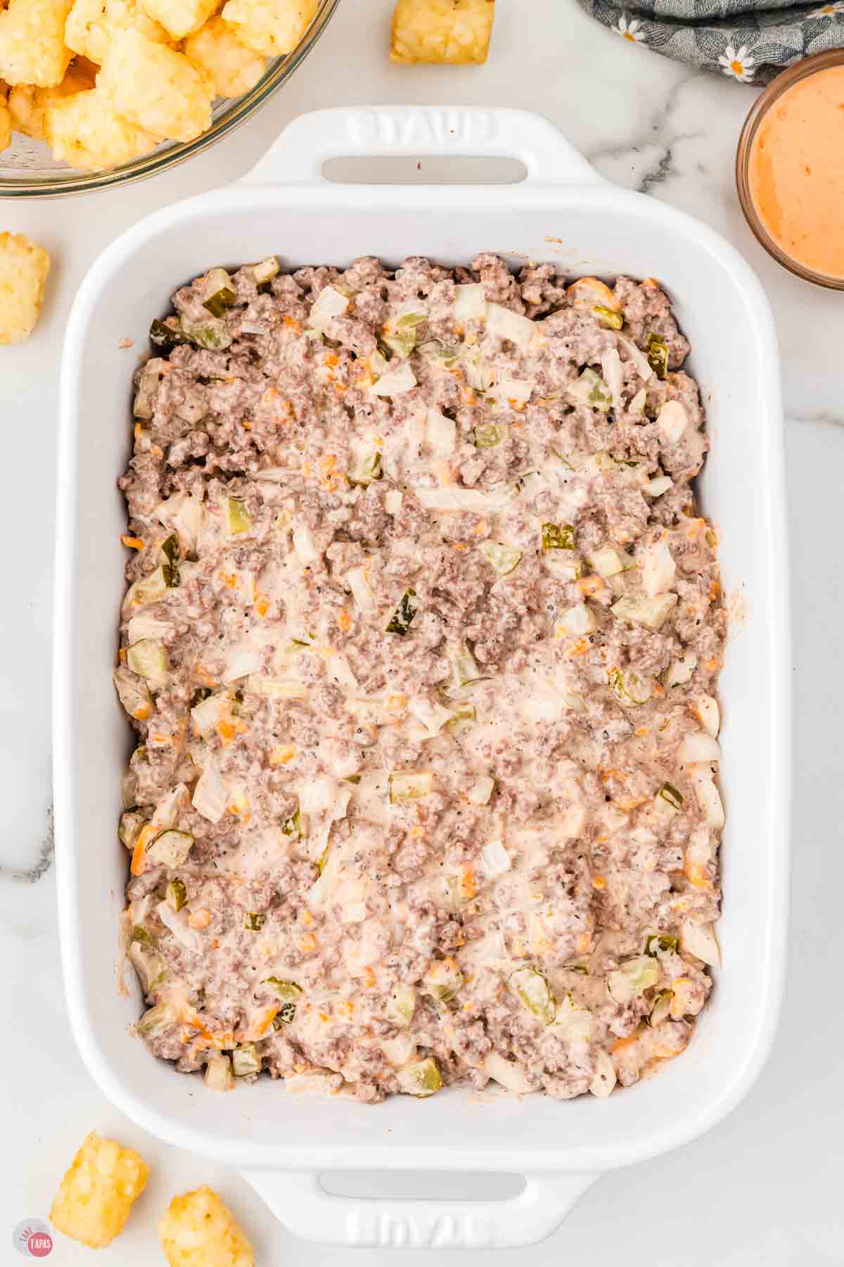 ground beef and sauce mixture in a white rectangle baking dish
