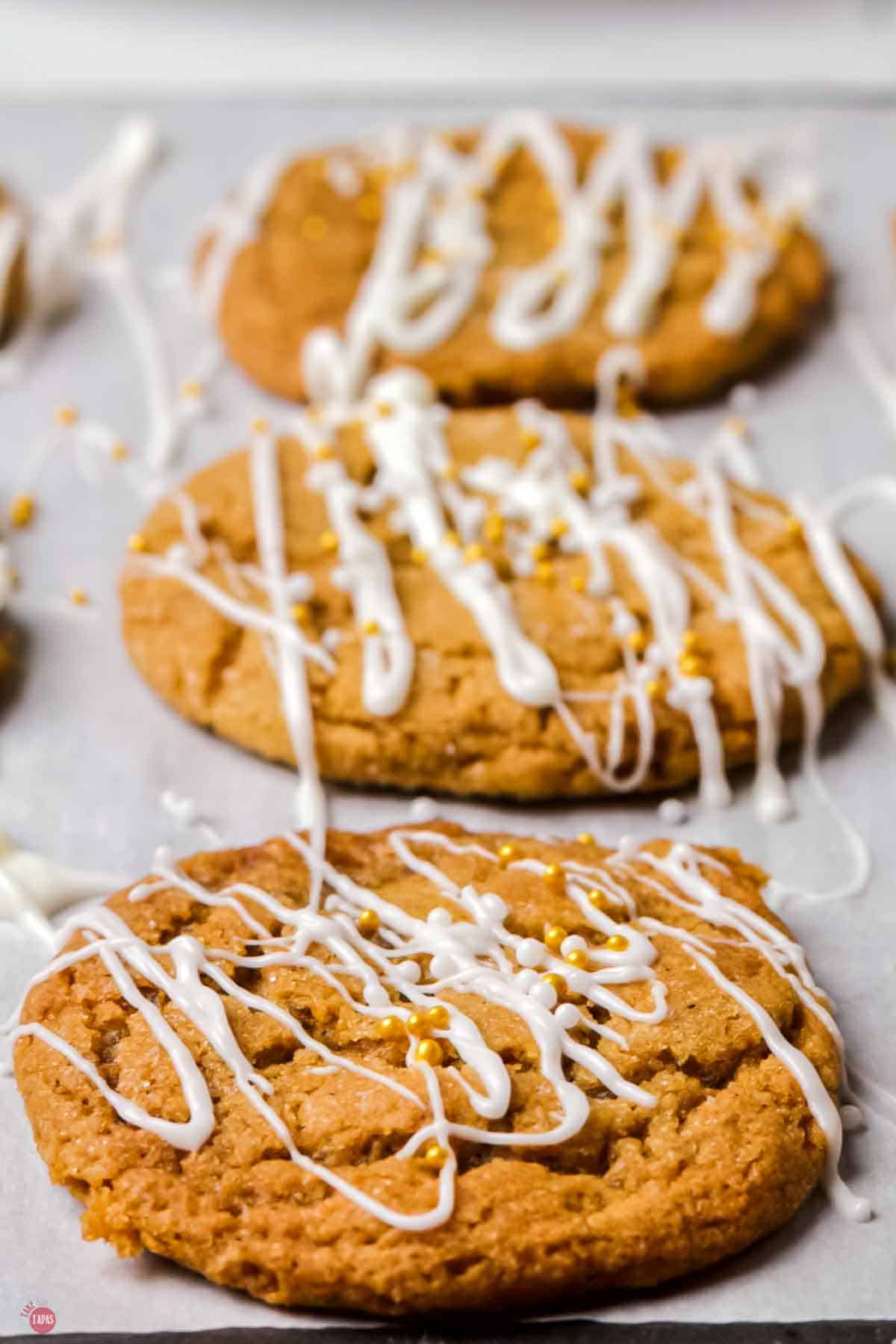 close up of cookies on a baking sheet topped with white chocolate and gold sprinkles