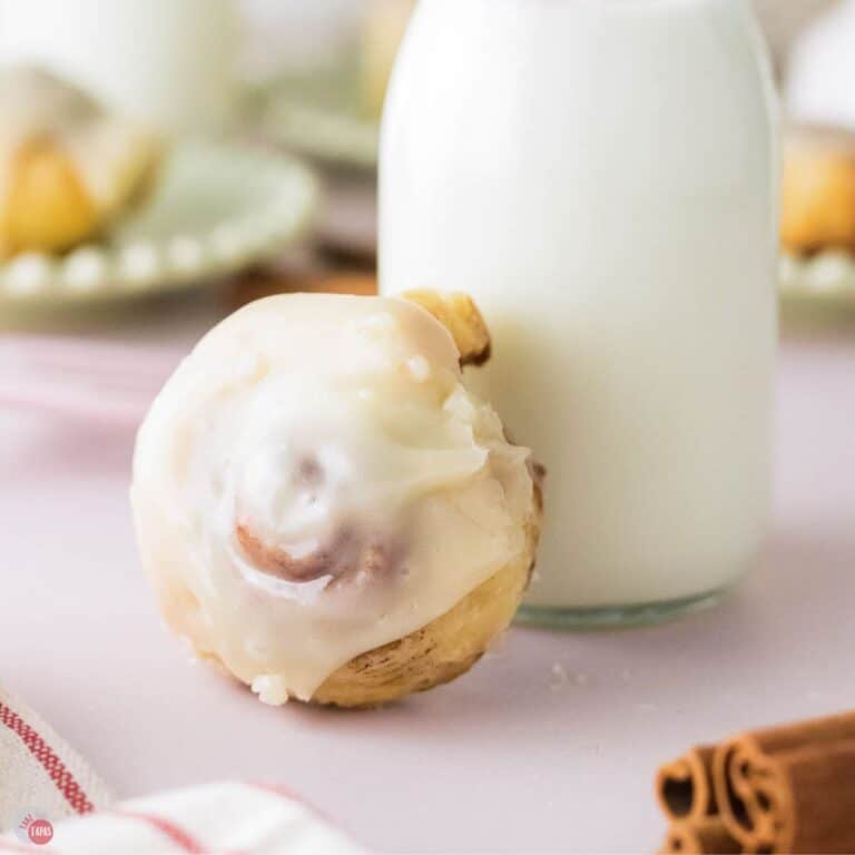cinnamon roll made of puff pastry resting against a small jar of milk