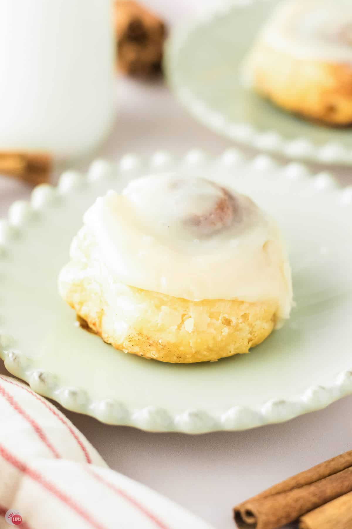 small green plate with a single cinnamon roll on it