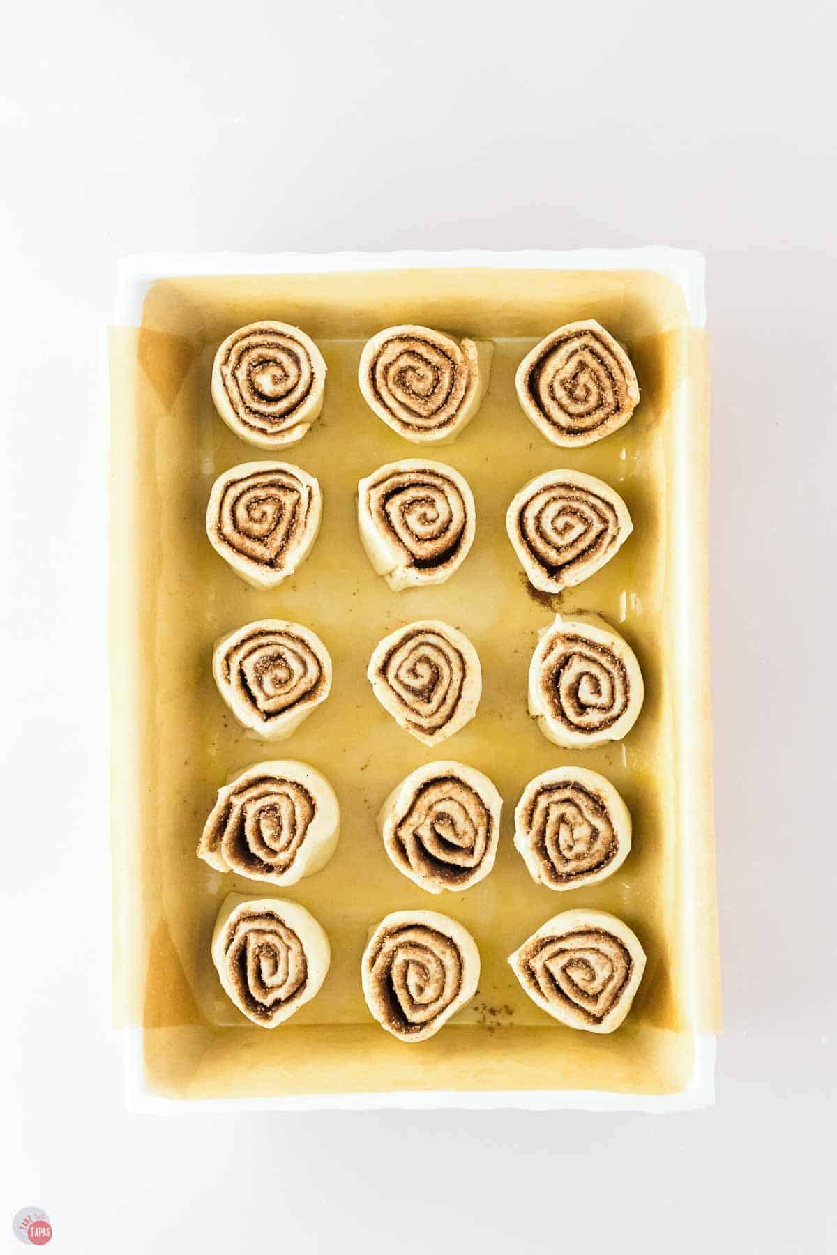 unbaked cinnamon rolls sliced and placed in a parchment lined baking sheet