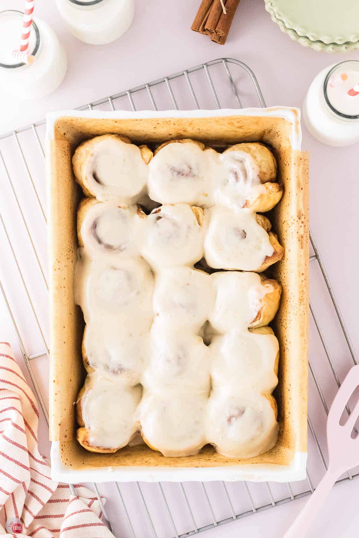 puff pastry cinnamon rolls with cream cheese frosting in a baking dish