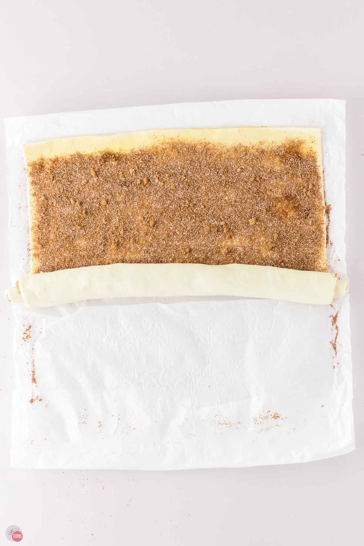 puff pastry with cinnamon being rolled into a long tube