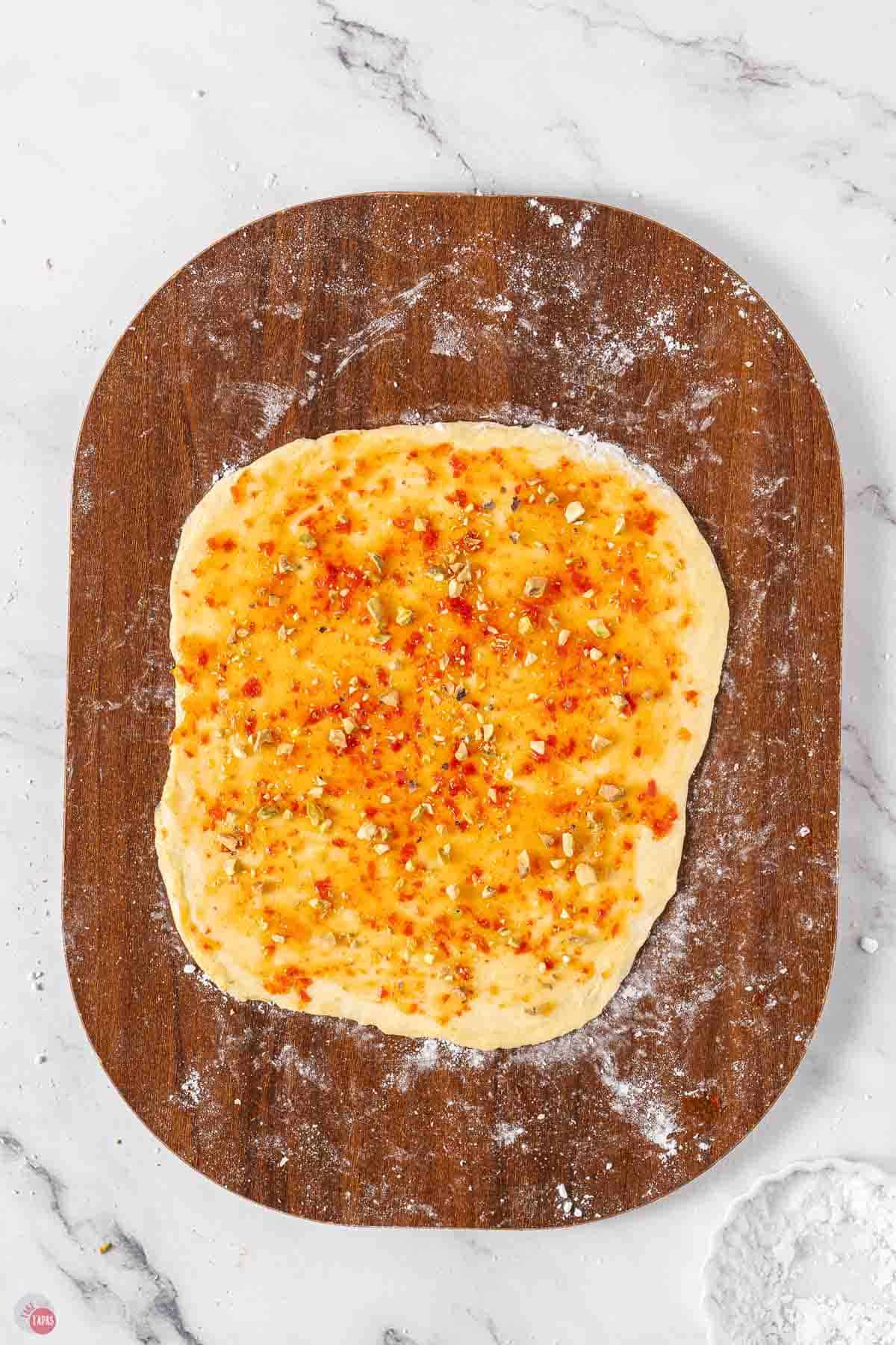 cookie dough rolled out on a cutting board topped with hot pepper jelly