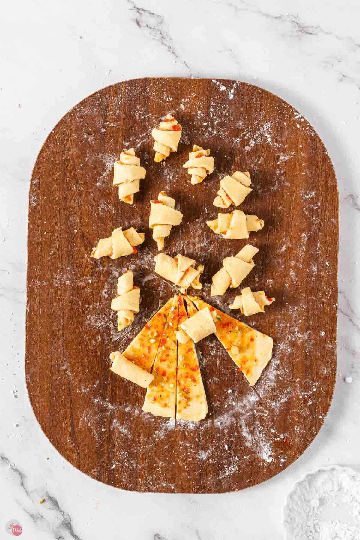 small, unbaked rugelach cookies on a wood cutting board