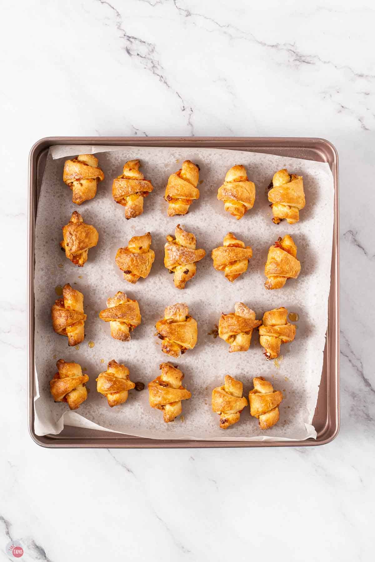 baked rugelach cookies on a baking sheet lined with parchment paper