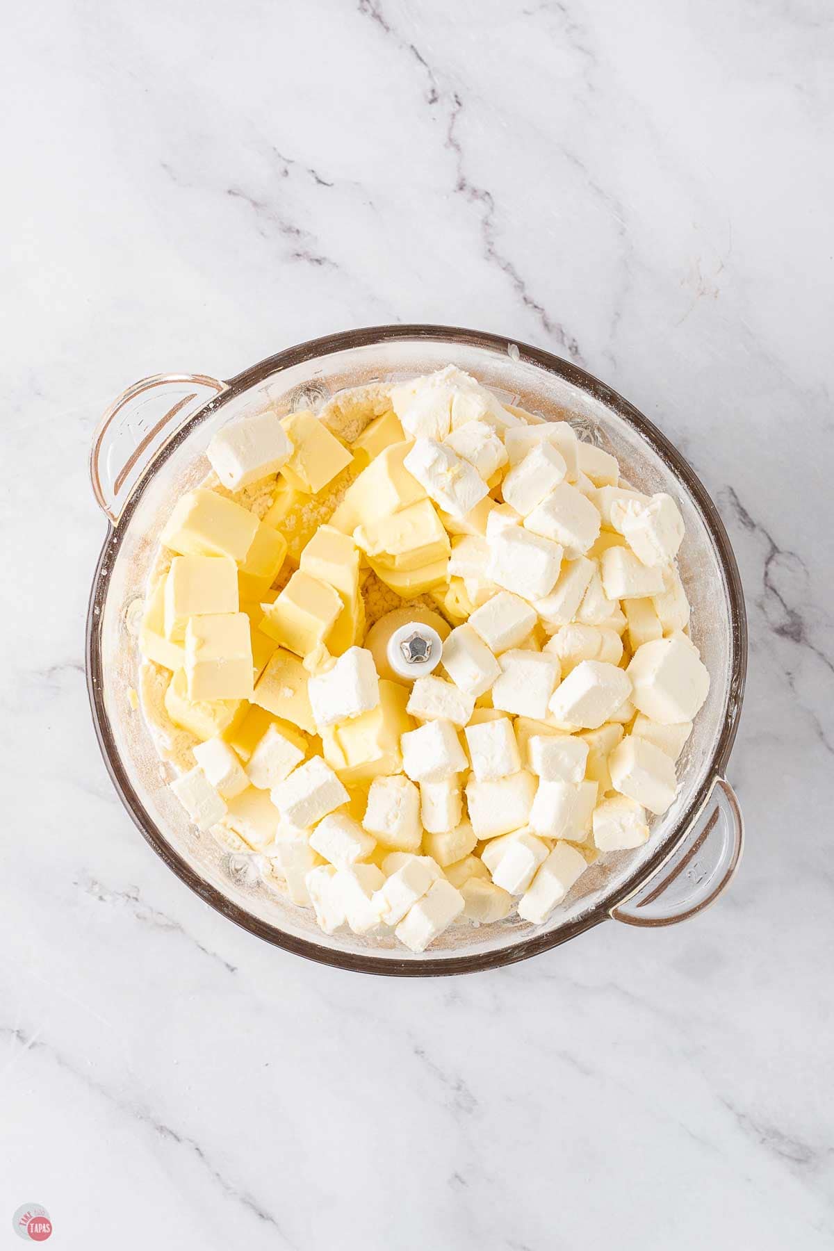 food processor bowl with cubed butter and cubed cream cheese