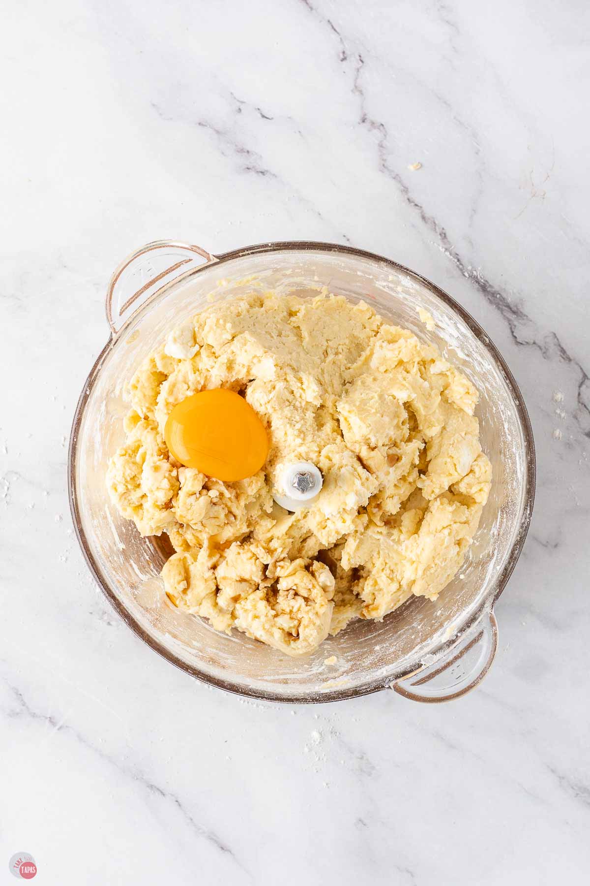 cookie dough in a food processor with an egg yolk on top